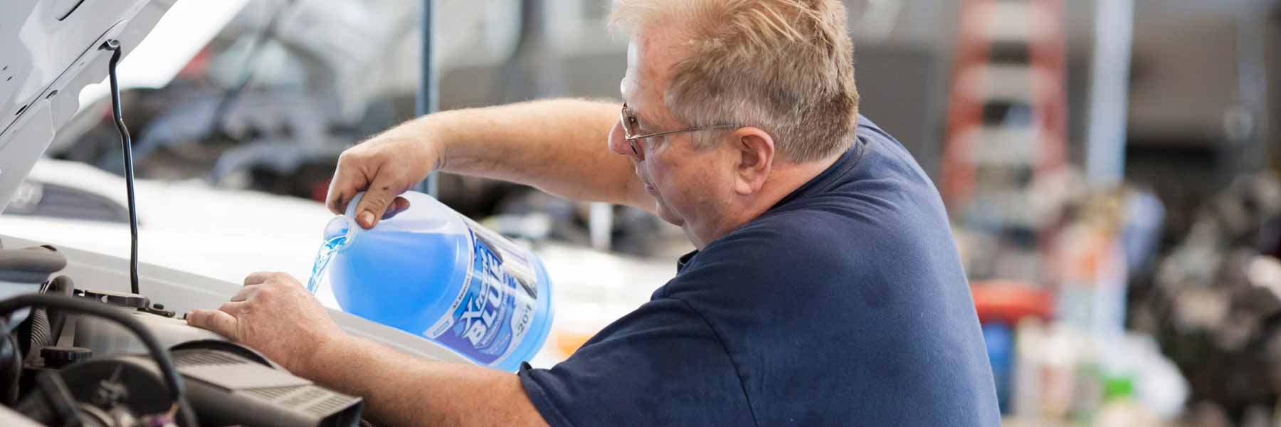 A man refills washer fluid in a vehicle.